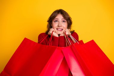 A happy vibrant female with brown hair in a red sweater holding shopping bags. Perfect for concepts of retail therapy, seasonal sales, and advertising in the fashion and lifestyle sectors. clipart