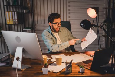 Businessman in a home office celebrating a successful moment while analyzing documents under natural light. A modern professional setting showcasing casual business attire and enthusiasm for a clipart