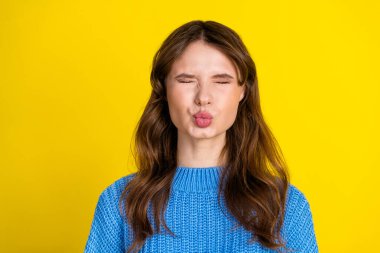 A cheerful young woman in a trendy knitted sweater poses playfully against a vibrant yellow background, portraying charm, humor, and personality. clipart