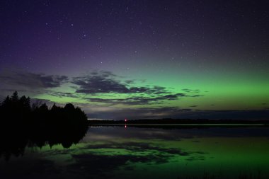 Kuzey Işıkları ya da Aurora Borielis dinamik yeşil ve pembe renkleri bir gölün üzerinde parlayan gökkuşağını gösteriyor