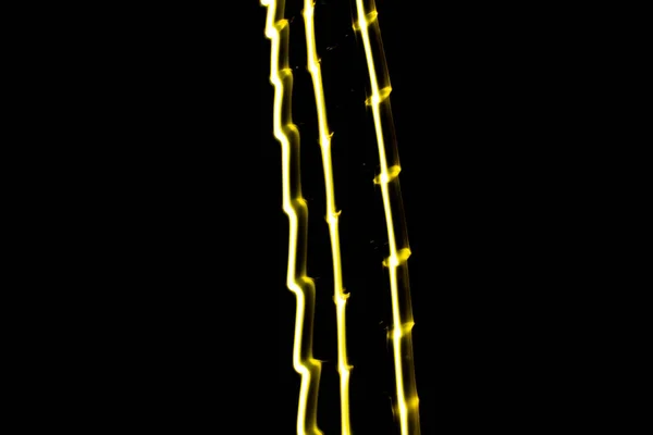 Yellow light lines on black background. Long exposure abstract lines. Light painting.
