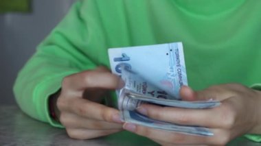 Türk lira banknotlarını sayan genç bir kadın.