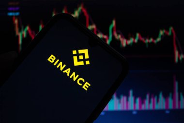 Akıllı telefon ekranında Binance mobil uygulama logosu görüntülendi. Arka planda bulanık borsa çizelgeleri var. Afyonkarahisar, Türkiye - 23 Aralık 2022.