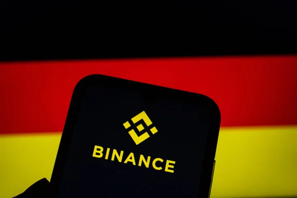 Akıllı telefon ekranında Binance logosu görüntülendi. Arka planda Almanya 'nın bulanık bayrağı var. Afyonkarahisar, Türkiye - 29 Aralık 2022.