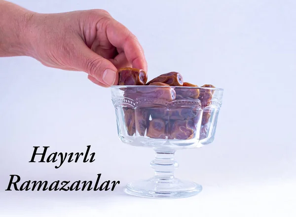 Hayirli Ramazanlar (Translate: Happy Ramadan). Hand taking date fruit from bowl. Copy space. Muslims holy month Ramadan.