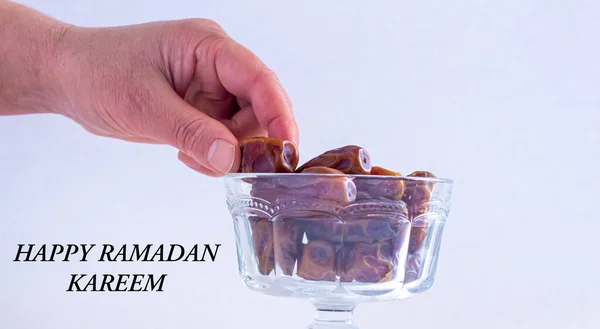 Happy Ramadan Kareem. Hand taking date fruit from bowl. Ramadan background photo with copy space. Holy month for Muslims.