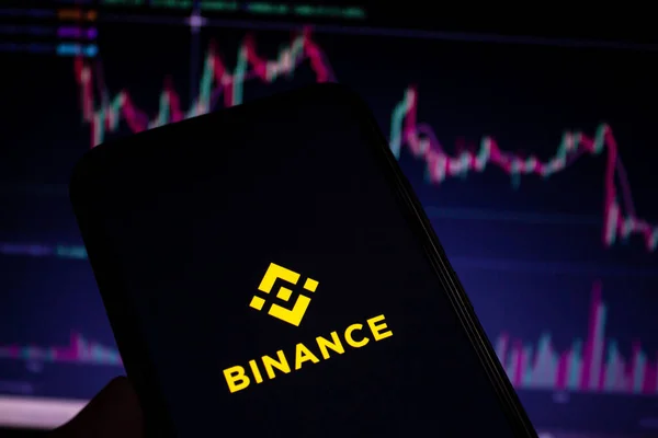Akıllı telefon ekranında Binance mobil uygulama logosu görüntülendi. Arka planda bulanık borsa çizelgeleri var. Afyonkarahisar, Türkiye - 23 Aralık 2022.