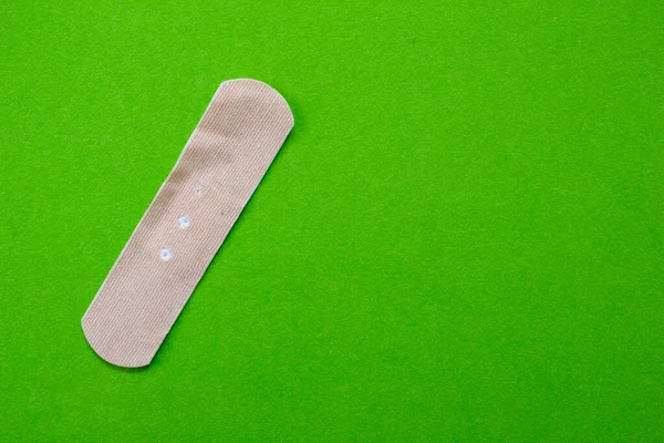 Band-aid isolated on green background. Top view of band aid with copy space.