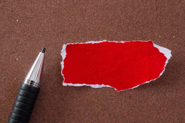Blank paper with pen on brown background. Top view of red paper piece with copy space.