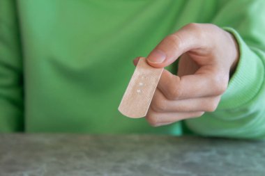 Woman holding adhesive plaster in her hand.