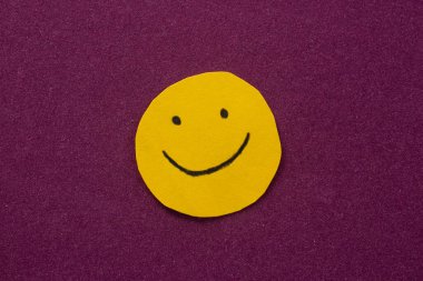 Smiley face drawn on yellow paper. Mental health and positivity concept.