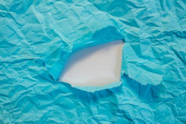 Blue paper hole on a white background. Copy space for advertising text. Crumpled paper torn.
