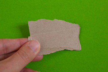 Hand holding torn paper on green background