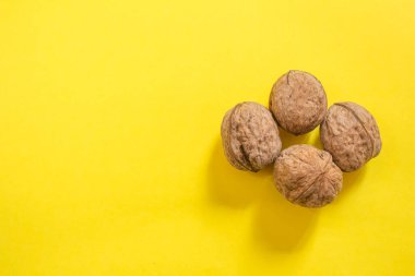 Top view of dried walnuts on yellow background with copy space