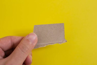 Hand holding torn paper on yellow background