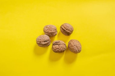 Top view of dried walnuts on yellow background with copy space