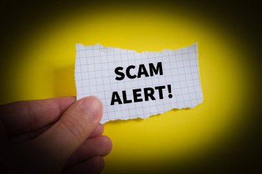 Scam Alert! word written on torn paper.