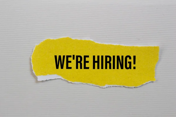 we\'re hiring! written on torn paper. Business concept photo.
