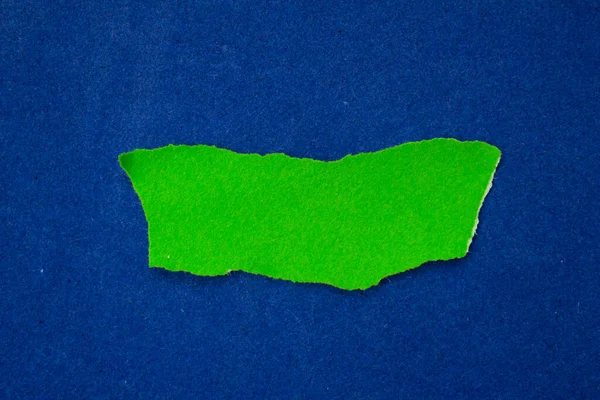 Green paper on blue background. Ripped paper piece.