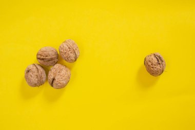A walnut stands alone, away from the others. The concept of exclusion, individuality, discrimination, loneliness.