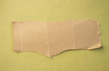 Torn cardboard paper on yellow background. Ripped paper piece with copy space.