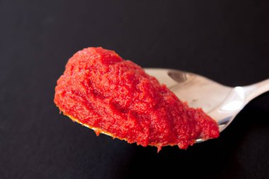 Tomato paste in a metal spoon. Close up photo of fresh tomato paste.