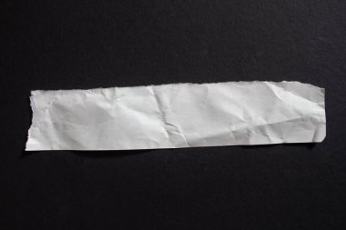 Crumpled torn paper piece isolated on a black background. Ripped paper sheet.