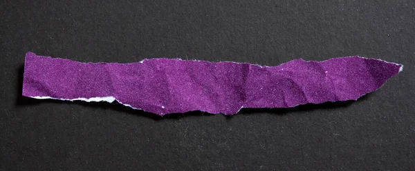 Crumpled purple torn paper piece isolated on a black background. Ripped paper sheet.