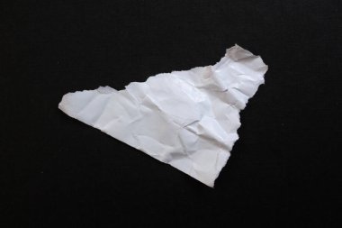 White torn paper piece isolated on black background