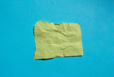 Mavi arka planda buruşmuş sarı kağıt parçası. Yırtık kağıt arkaplanı.