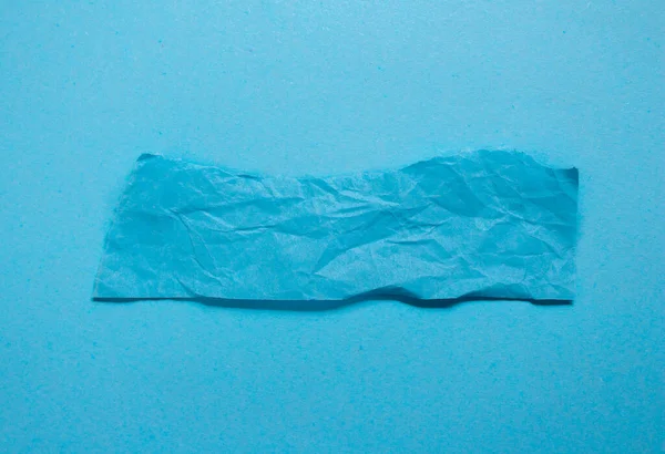 Crumpled blue paper on a blue background. Torn paper background with copy space.