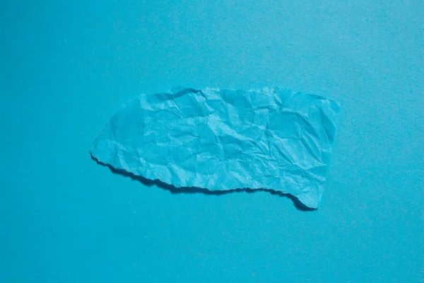 Crumpled blue paper on a blue background. Torn paper background with copy space.