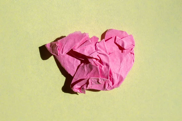 Crumpled pink paper piece on a yellow background. Torn paper background.