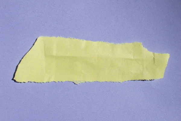 Crumpled yellow paper piece on a purple background. Torn paper background.