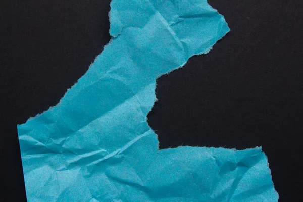Blue torn paper background with copy space for text. Ripped paper on a black background.