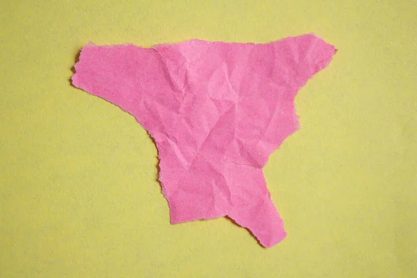 Crumpled pink paper piece on a yellow background. Torn paper background with copy space for text.