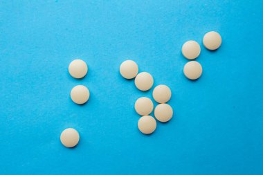 Mavi arka planda izole edilmiş sarı haplar. Üst manzara, düz uzanma.