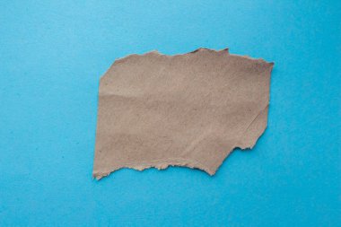 Yırtılmış karton parça mavi bir arka planda izole edilmiş. Üst görünüm, alanı kopyala.