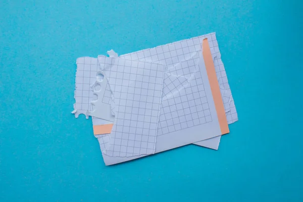 stock image Ripped graph paper pieces isolated on a blue background. Torn checkered papers.