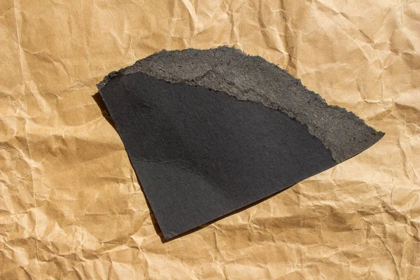 黑色撕破的纸在皱巴巴的背景上 带有复制空间的牛皮纸片 — 图库照片