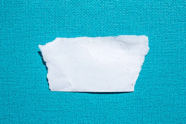 Ripped paper piece on a blue background. Torn paper with copy space for text.