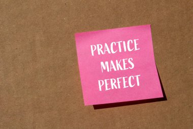 Pratik, kahverengi arkaplanlı pembe kağıt üzerine yazılmış kelimeleri mükemmel hale getirir. Kavramsal pratik mükemmel bir sembol yapar. Boşluğu kopyala.