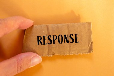 Turuncu arkaplanlı karton kağıt parçasına yazılmış bir cevap. Kavramsal tepki sembolü. Boşluğu kopyala.