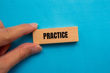 Ahşap blokta mavi arka planda yazılmış pratik kelimesi. Kavramsal uygulama sembolü. Boşluğu kopyala.