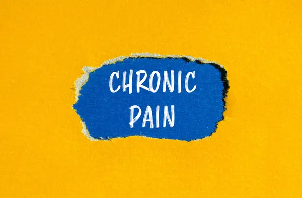 Chronic pain words written on ripped yellow paper with blue background. Conceptual chronic pain symbol. Copy space.