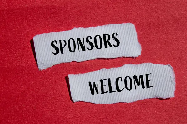 Sponsorlar, kırmızı arkaplanlı yırtık beyaz kağıt parçalarına yazılmış kelimeleri hoş karşılıyorlar. Kavramsal sponsorlar hoş geldin sembolü. Boşluğu kopyala.
