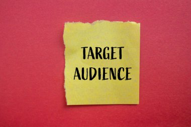 Kırmızı arkaplanlı sarı kağıt parçasına yazılmış hedef kitle sözcükleri. Kavramsal hedef kitle sembolü. Boşluğu kopyala.