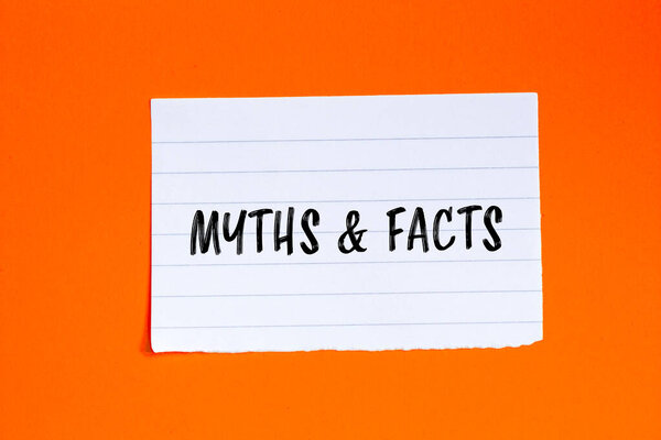Myths & facts words written on torn paper with orange background. Conceptual myths & facts symbol. Copy space.