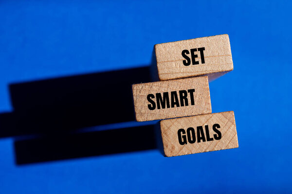 Set smart goals words written on wooden blocks with blue background. Conceptual set smart goals symbol. Copy space.