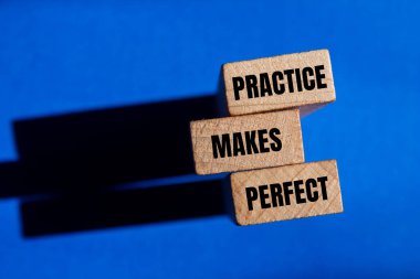 Pratik, ahşap bloklara mavi arkaplan ile yazılmış mükemmel kelimeleri oluşturur. Kavramsal pratik mükemmel bir sembol yapar. Boşluğu kopyala.